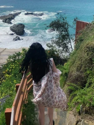 Woman wearing a lightweight floral print cardigan as a relaxed shoulder tote bag on a coastal hillside trail