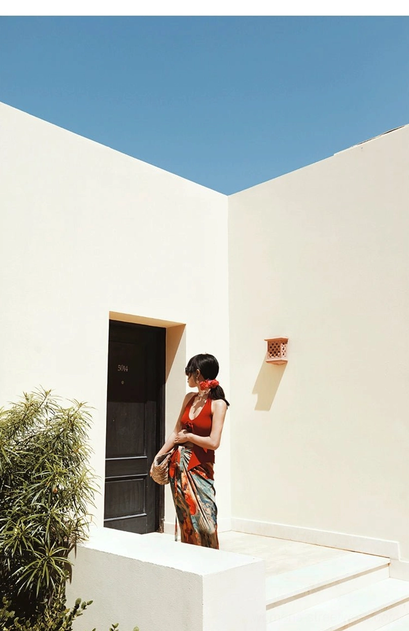 Rear three-quarter view of a flowing abstract print maxi skirt with side waist tie styled beside a villa doorway