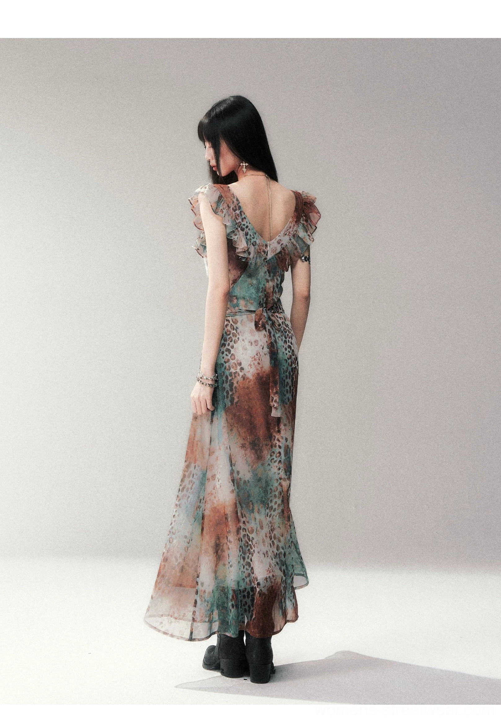 Side back view of a flowy open-back leopard print maxi dress with ruffle trim, tied waist detail, and ankle-grazing skirt