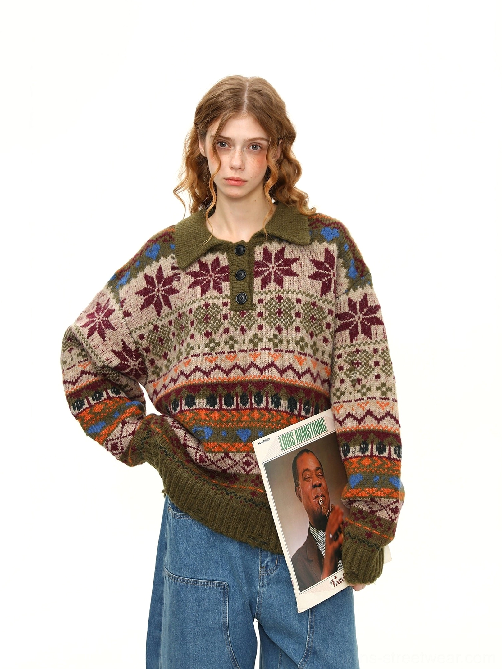 Three-quarter front view of an oversized green Fair Isle polo sweater with retro snowflake and geometric knit patterns styled with wide-leg blue jeans and a vintage vinyl record