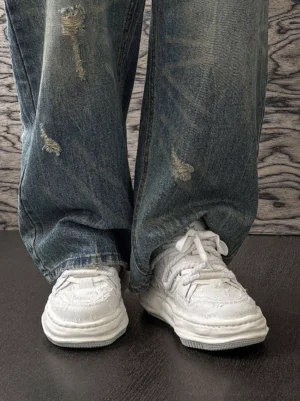 Frayed canvas platform sneakers worn with ripped blue denim jeans in a low-angle Y2K streetwear outfit