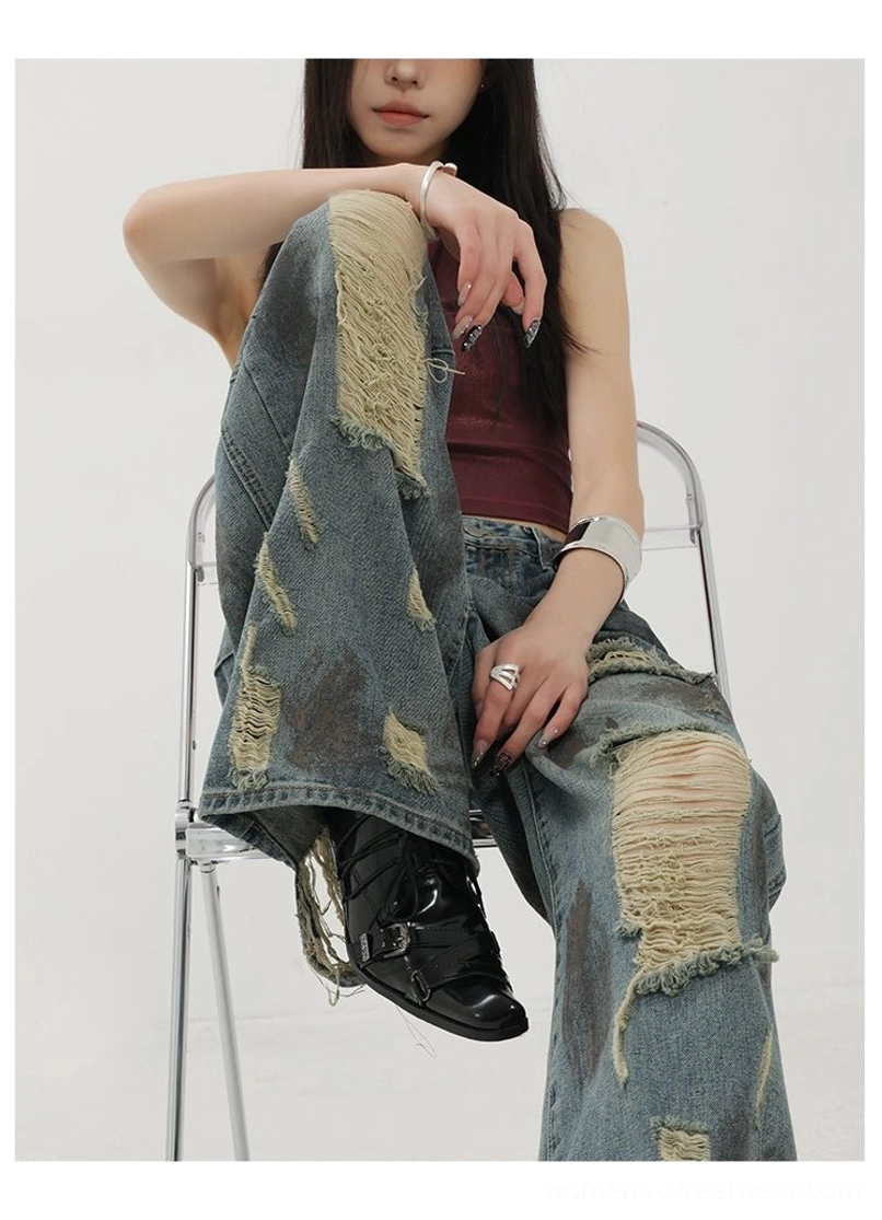 Close-up seated view showing frayed knee patches and vintage washed distressed denim texture on wide-leg jeans