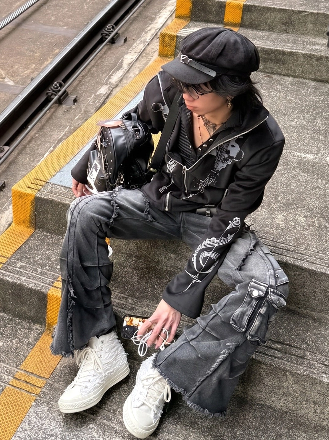Fringed white high-top canvas sneakers worn with dark punk streetwear outfit on subway steps