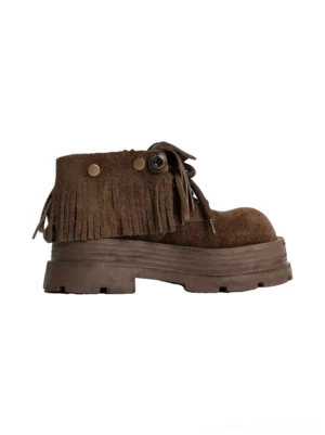 Side view of a fringed suede platform ankle boot showing the fold-over cuff, long tassel fringe, metal button detail, and thick rubber lug sole