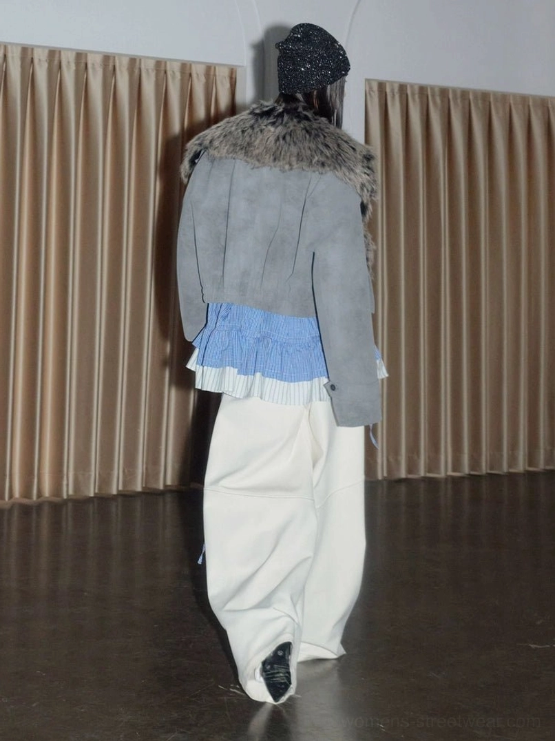 Back view showing the textured gray suede-look body and faux fur collar of a cropped streetwear jacket styled with loose white pants