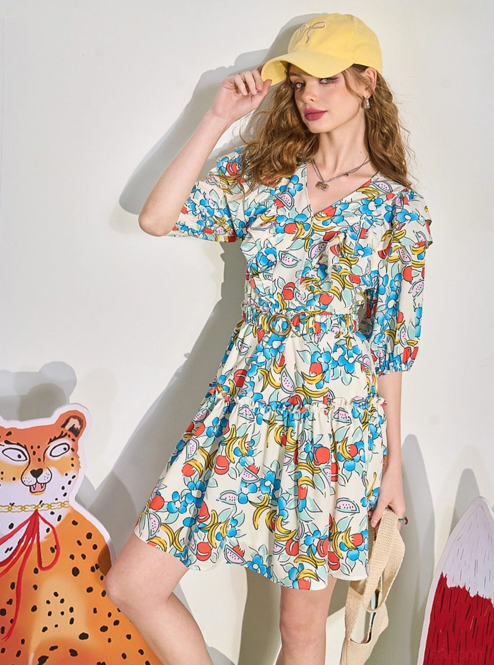 Front outfit view of fruit print V-neck mini dress with ruffle neckline, puff sleeves, and cinched waist
