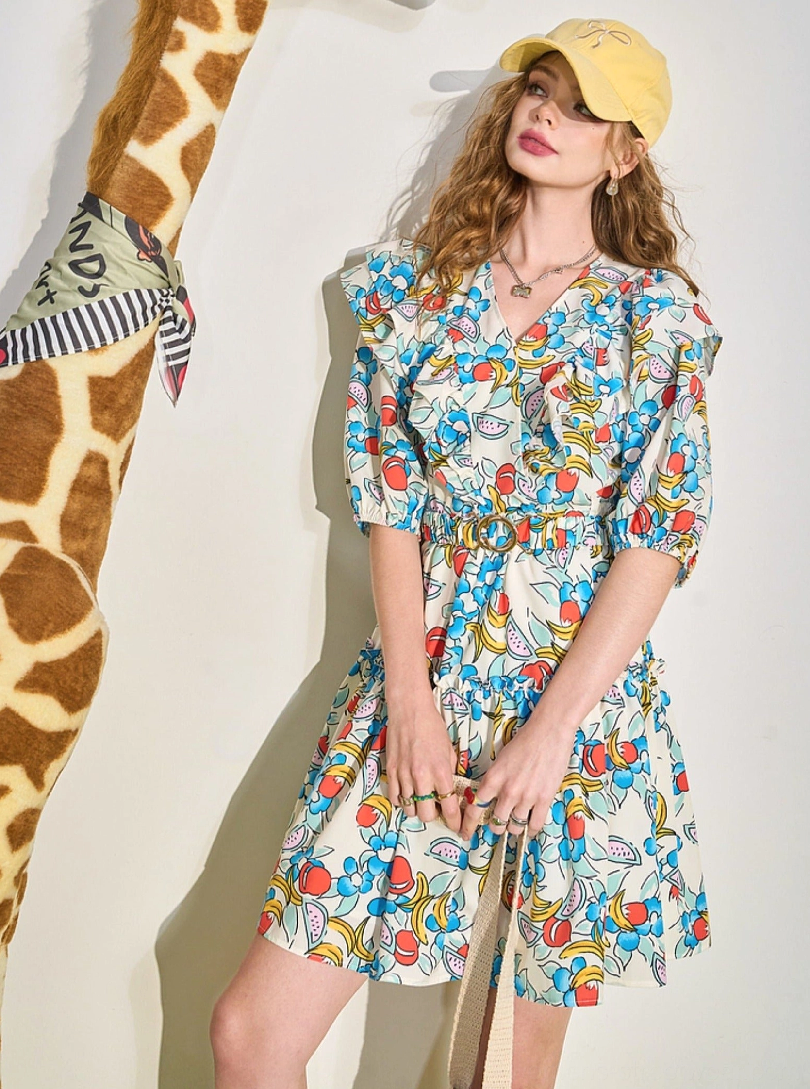 Side view showing the playful silhouette and tiered ruffle hem of a fruit print V-neck mini dress
