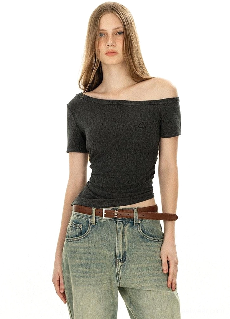 Full body front view off-shoulder dark grey minimalist tee slim fit with boat neckline chest logo and vintage washed jeans streetwear