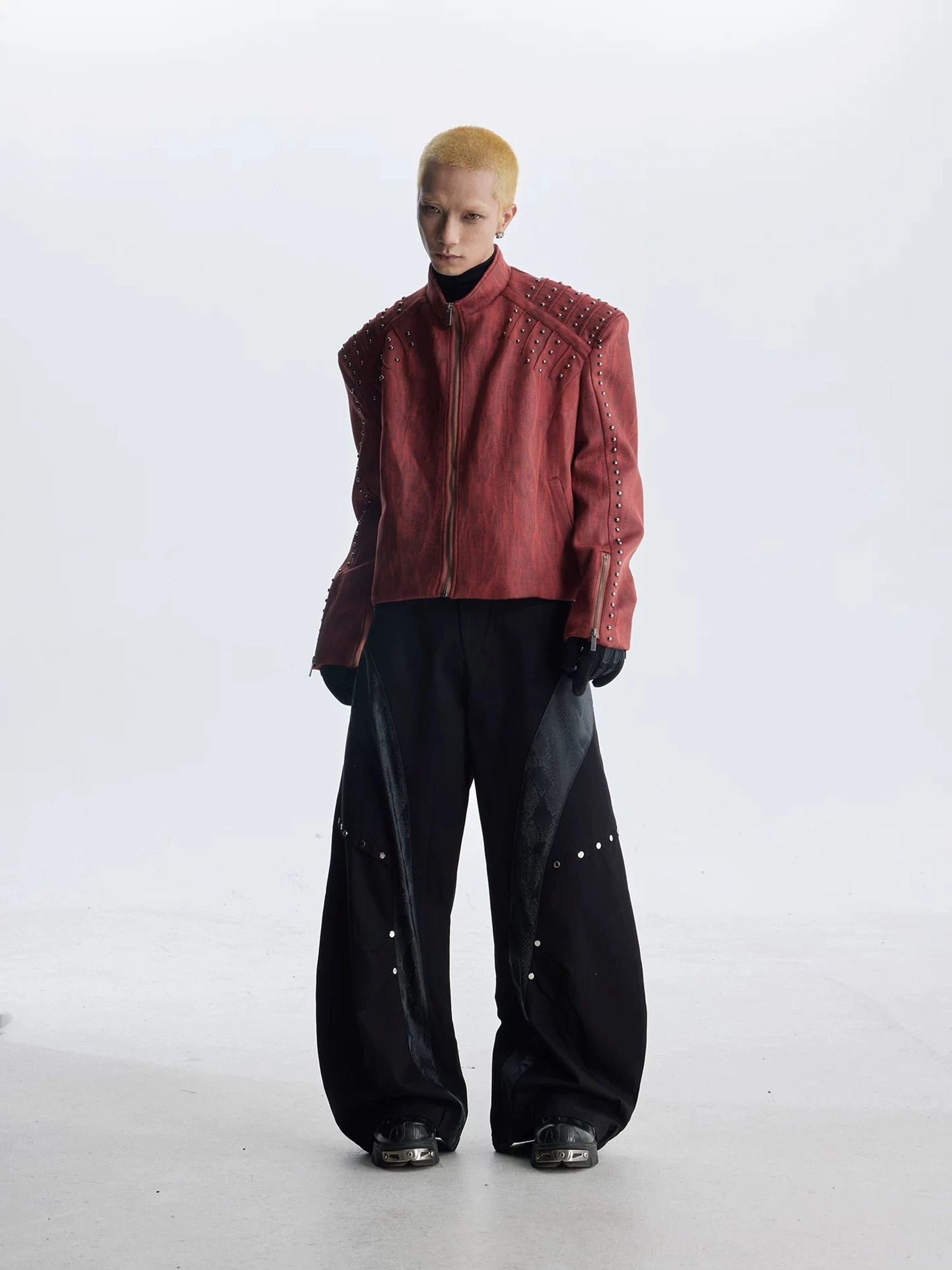Futuristic faux leather biker jacket with exaggerated shoulders metallic rivets and sharp avant-garde streetwear styling