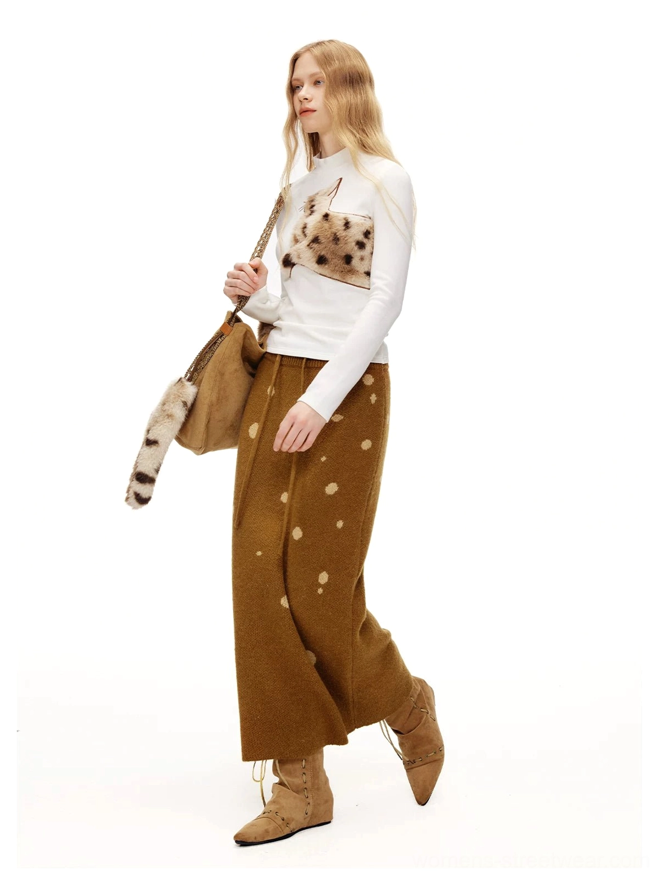 Side view of a white fuzzy cat mock neck tee styled with a brown polka-dot skirt and cat-themed crossbody bag