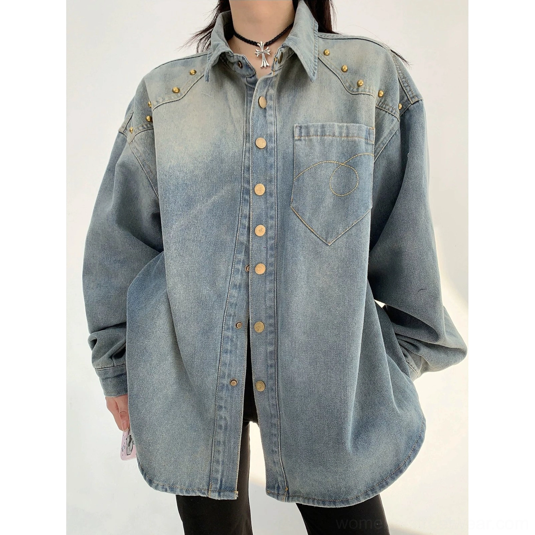 Front close-up of a vintage-inspired faded blue oversized denim shirt jacket with gold shoulder rivets, snap-front closure, and stitched chest pocket