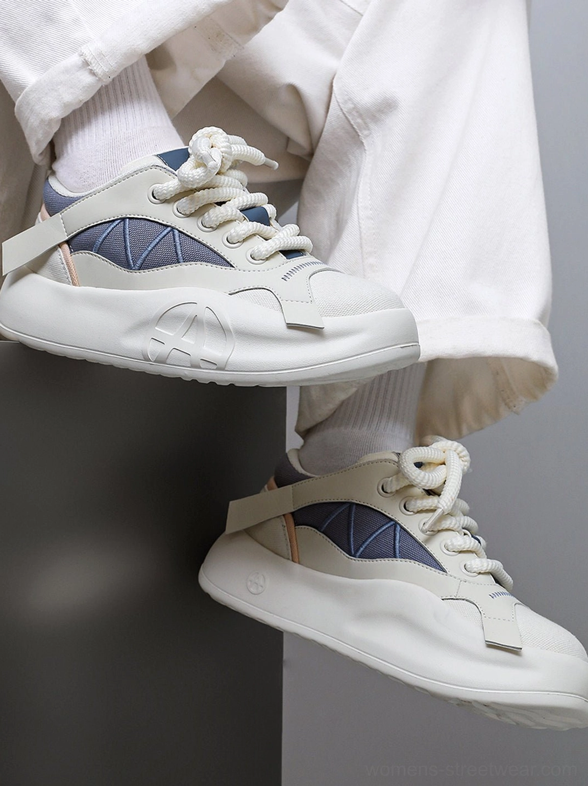 Geometric panel platform runner sneakers on feet with rolled white trousers, viewed from above to show the uppers and heel tabs