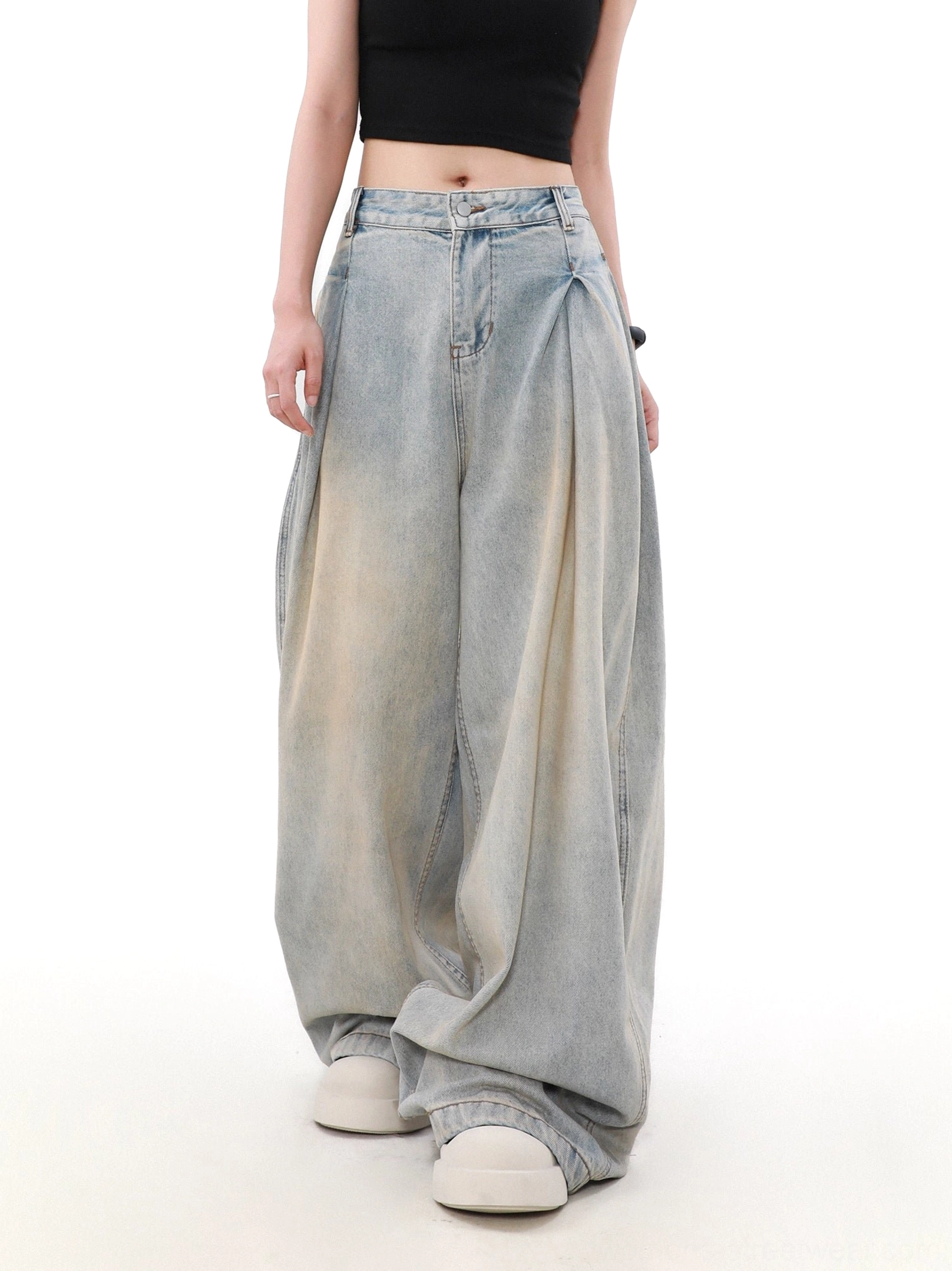 Front view of women’s loose ultra-wide-leg jeans with zipper fly, deep front pleats, high waist, and faded light blue denim finish