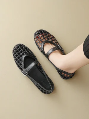 Sparkly black glitter caged Mary Jane jelly flats worn on foot with adjustable buckle strap and hollow grid upper