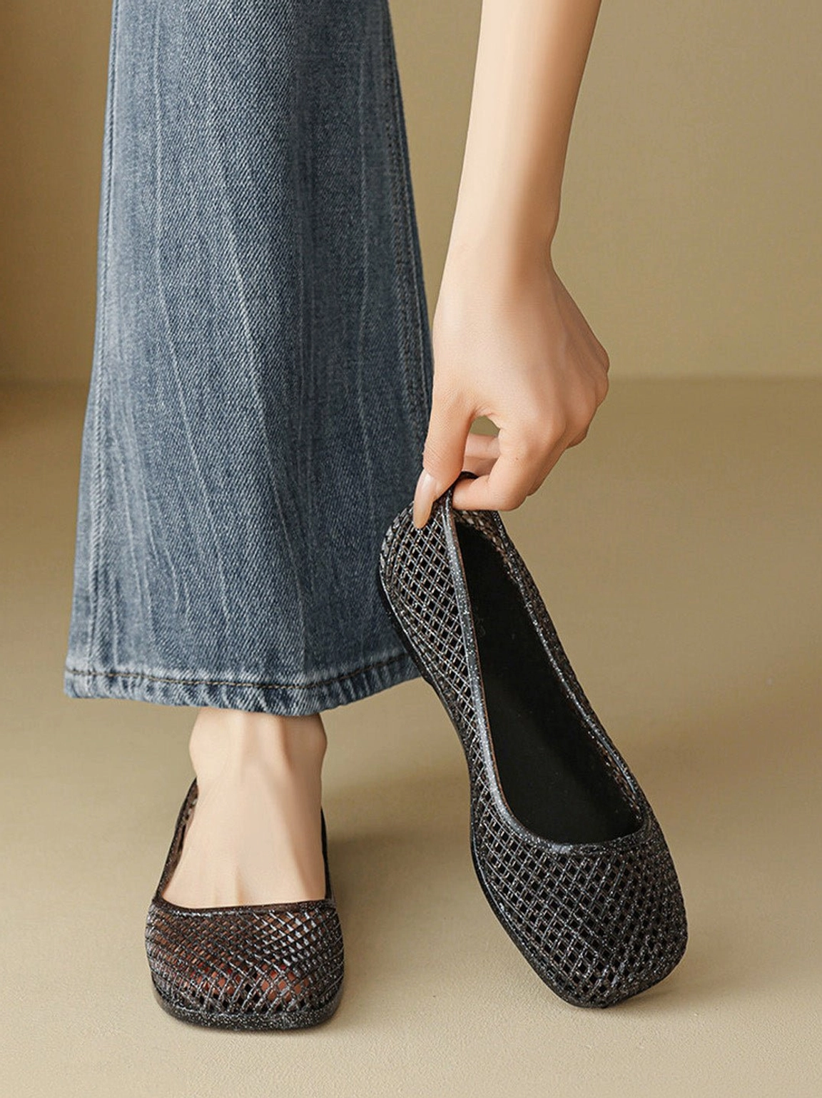 Close-up of a hand slipping into black woven mesh jelly ballet flat with easy slip-on design