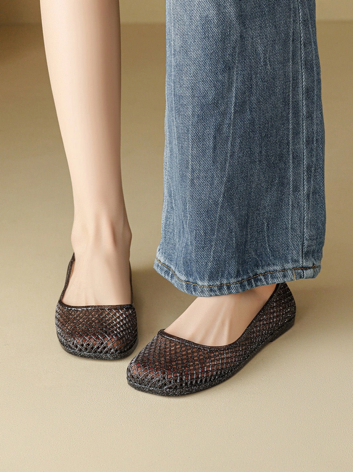 Model wearing dark glitter mesh jelly ballet flats with blue wide-leg jeans in a casual streetwear outfit