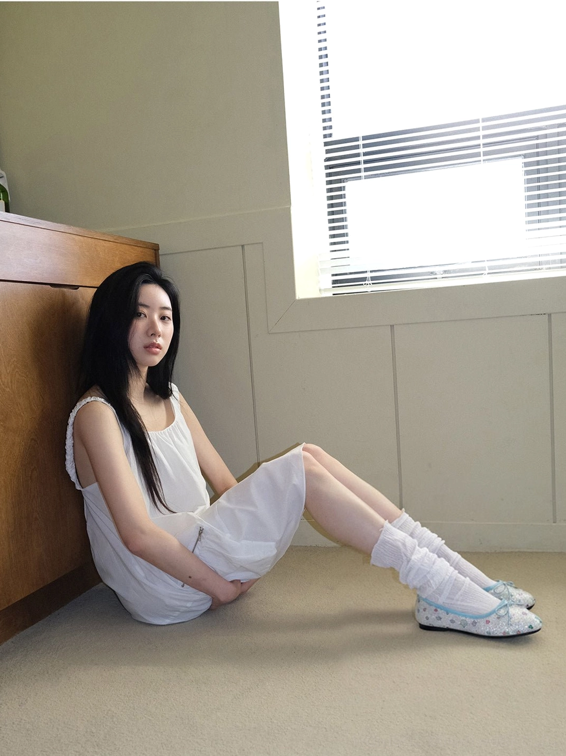 Side view of glitter star print bow ballet flats worn with a white dress and ruffled socks