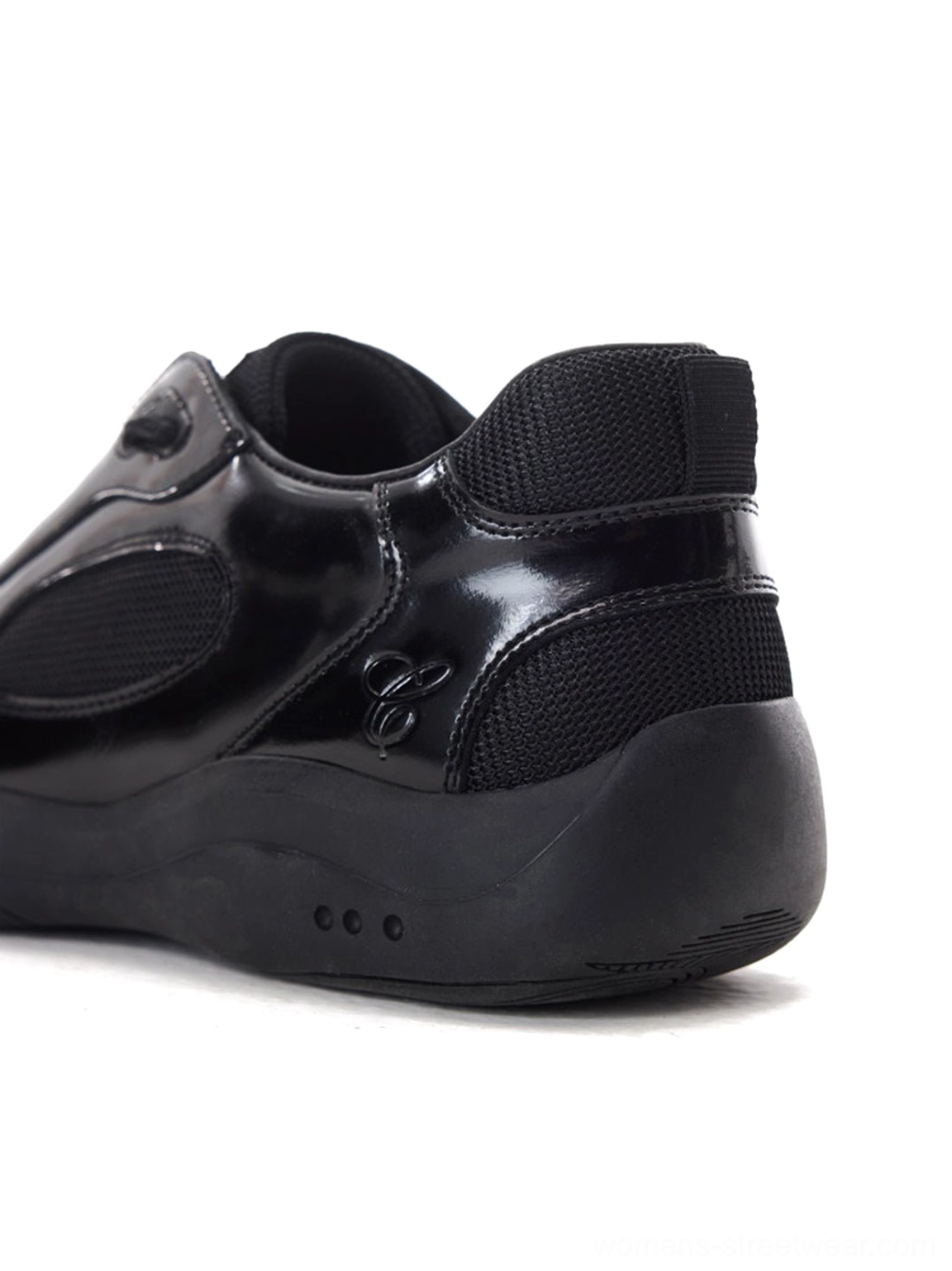 Glossy black retro runner sneaker shown from the rear side with padded mesh heel collar and sculpted outsole details