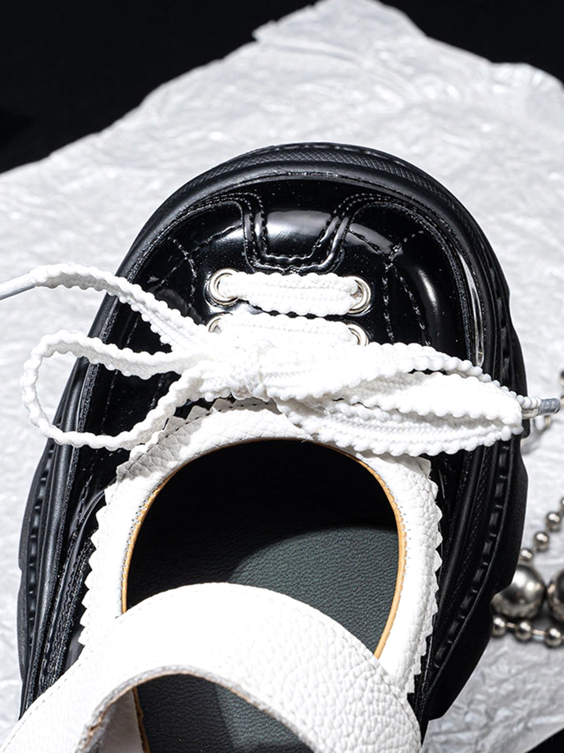 Glossy black and white platform Mary Jane shoes with contrast straps and chunky streetwear outsole displayed in a detailed product view