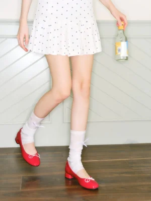 Red glossy ballet pumps styled with a polka dot mini dress and white lace-up socks in a Korean streetwear outfit