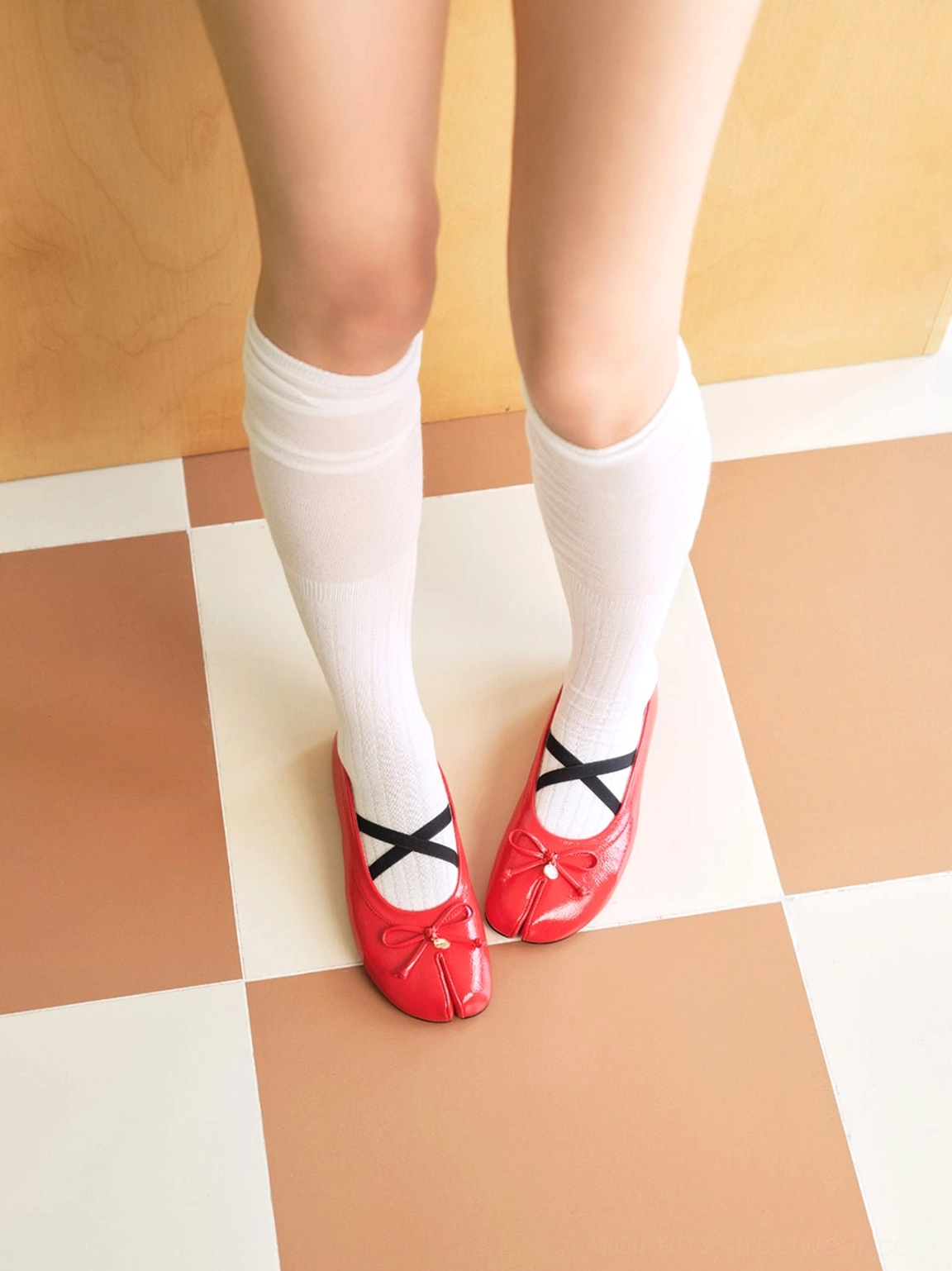 Top rear view of glossy red split-toe Mary Jane ballet flats with black cross straps and white knee-high socks