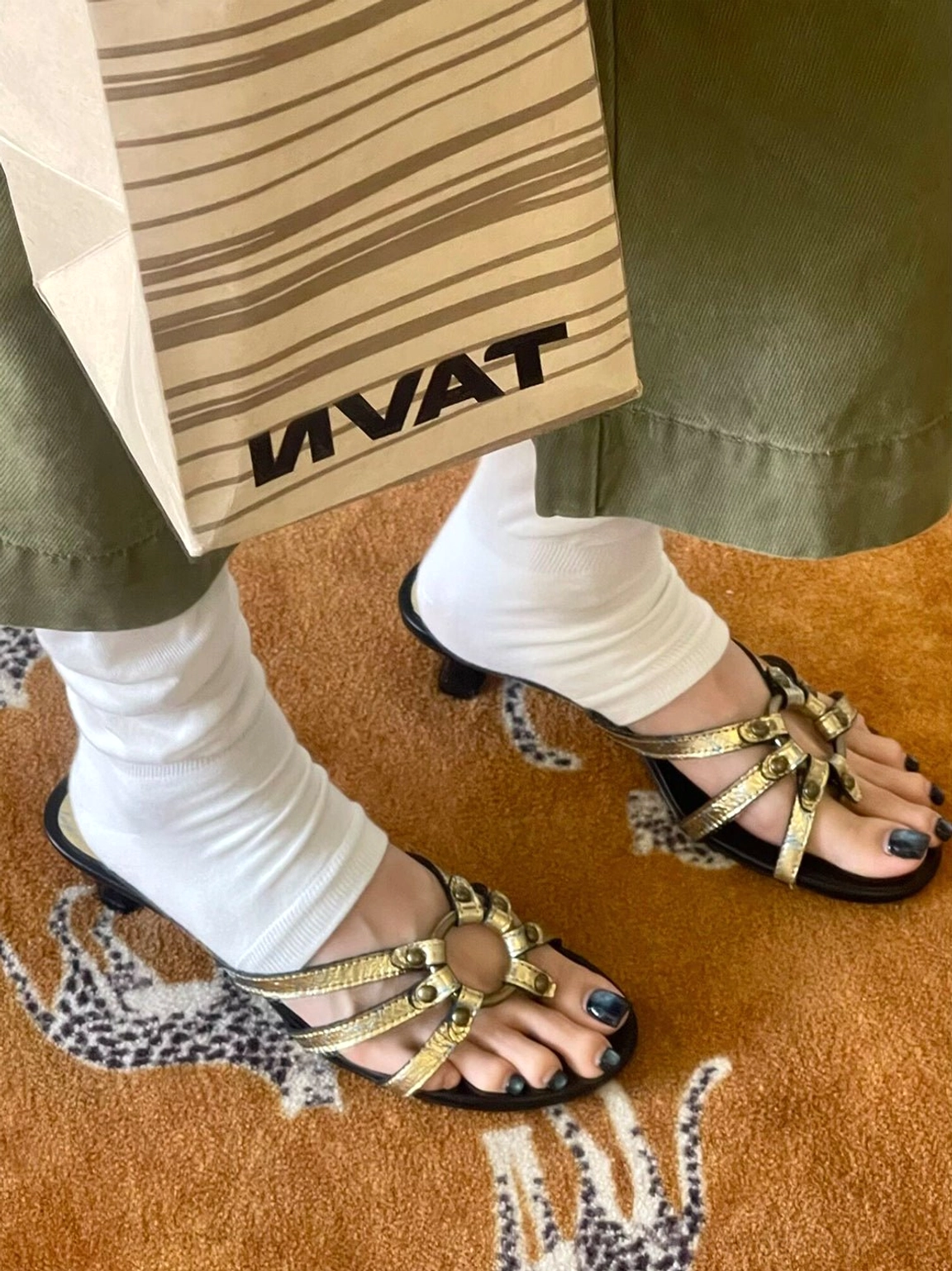 Top-down view of gold metallic kitten-heel sandals styled with white socks and olive green trousers for a Korean streetwear look