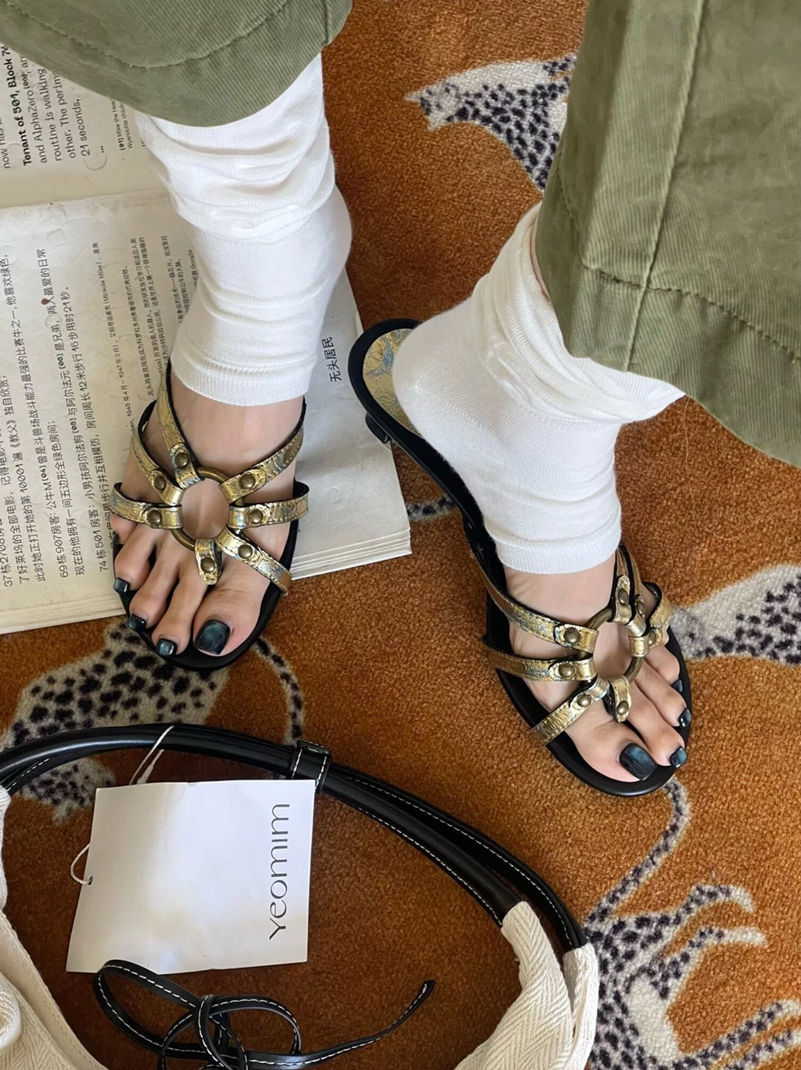 Close-up overhead view of gold crackle strap sandals showing crisscross detailing, circular hardware, and open square toes