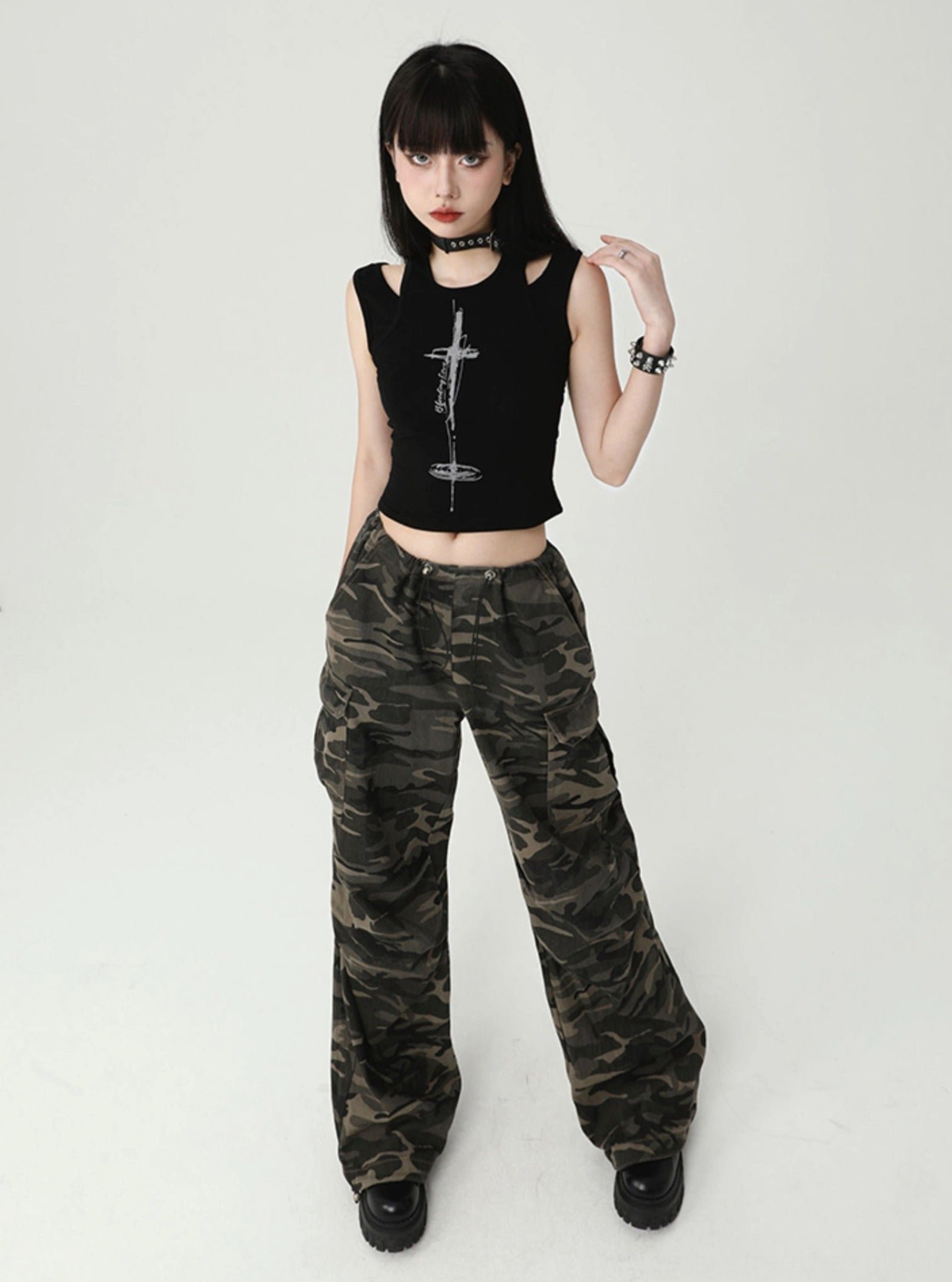 Three-quarter view of a black gothic cross cutout tank top with cropped silhouette, silver chest graphic, ribbed fabric, and Seoul-inspired styling