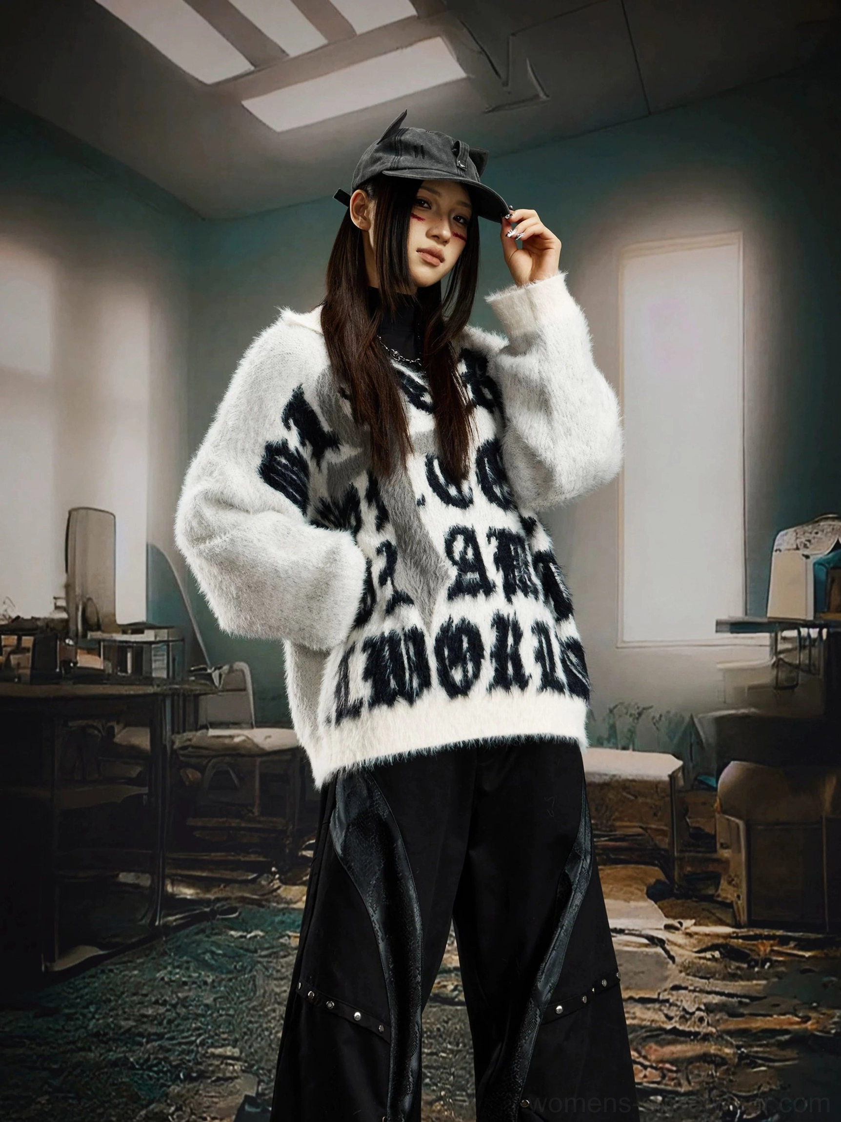 White fuzzy gothic cross sweater shown from the front on a female model with a cat ear bucket hat and black wide leg streetwear pants in an industrial studio