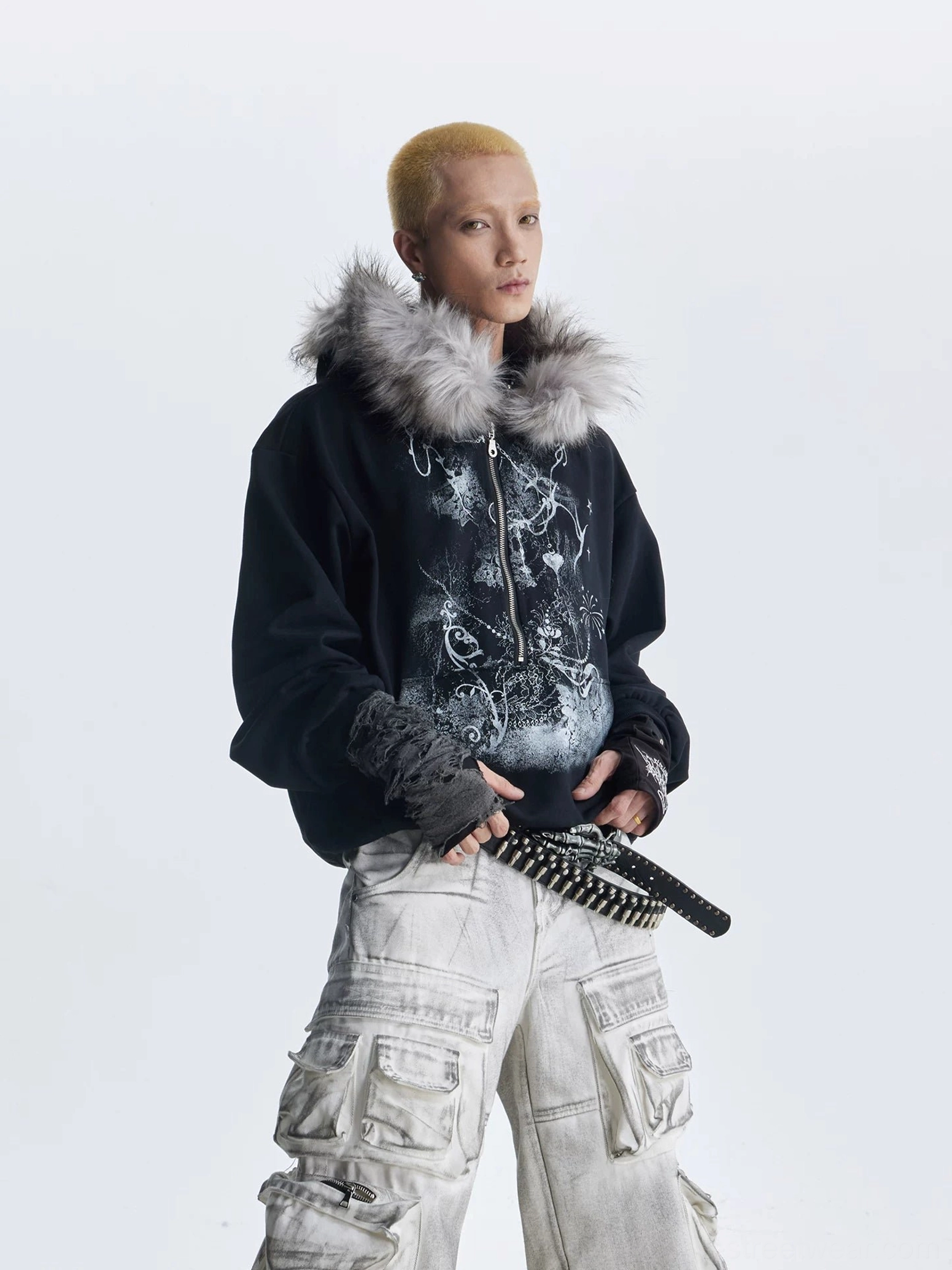 Three quarter view of black gothic faux fur trim graphic zip hoodie with cargo pants and chain accessories