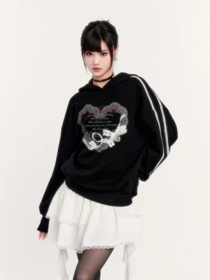 Asian model wearing a black gothic heart print hoodie with white sleeve stripes and a white lace ruffle cake skirt