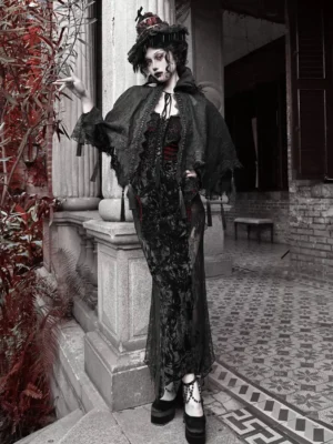 Model wearing a black gothic lace tassel cape with high collar over a formal dress in a vintage European courtyard