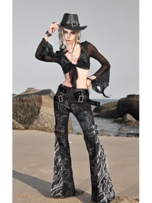 Three quarter front view of black gothic western dragon print flare jeans with grey dragon graphics, frayed hems, buckle waist straps, and coastal streetwear styling