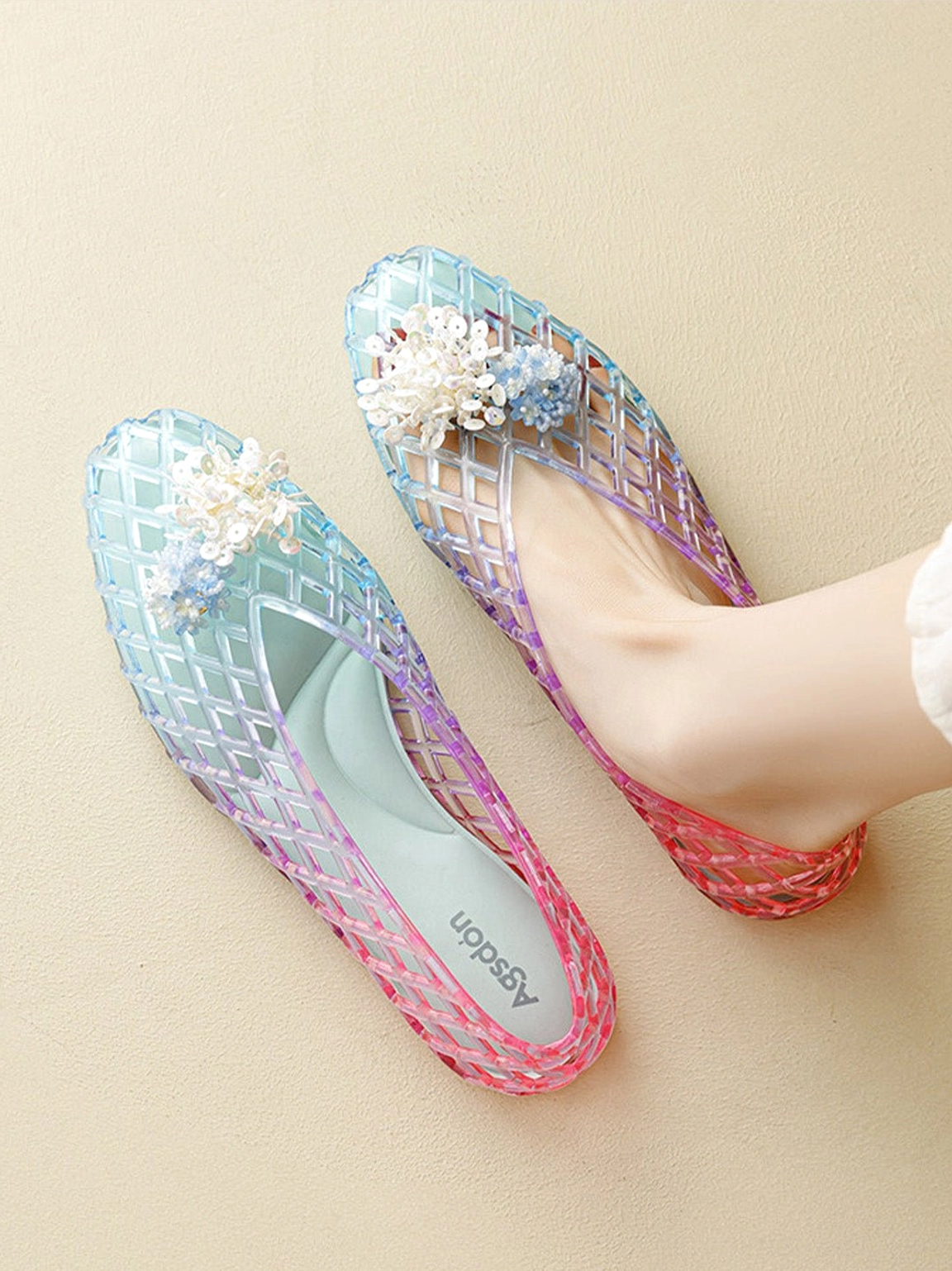 Three quarter view of gradient jelly ballet flats with open lattice texture white flower ornament and translucent construction