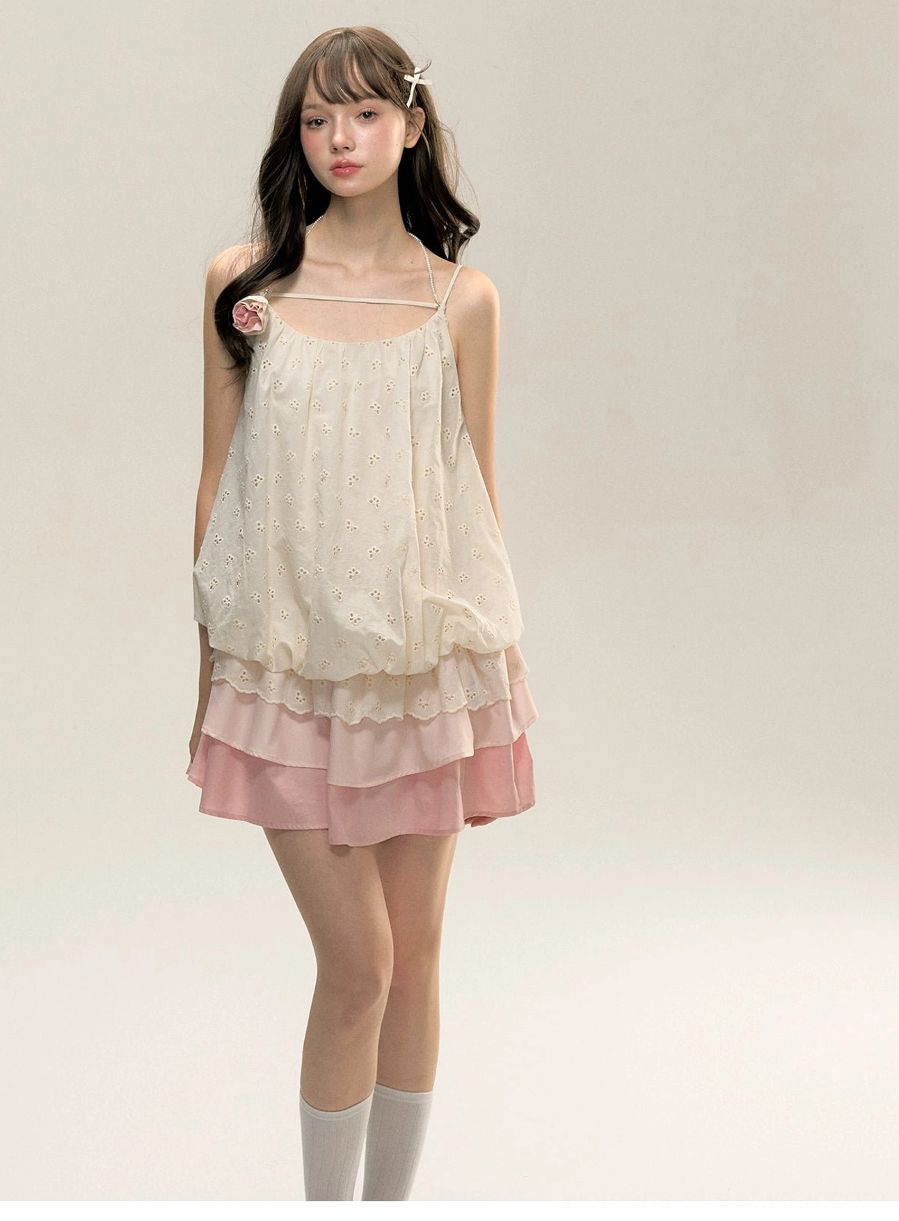 Full front view of romantic cream and gradient pink floral tiered mini slip dress styled with white crew socks for a playful streetwear look