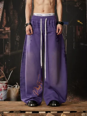Gradient purple Y2K wide leg streetwear sweatpants with elastic drawstring waist, handwritten graffiti graphics, and ultra-baggy stacked silhouette