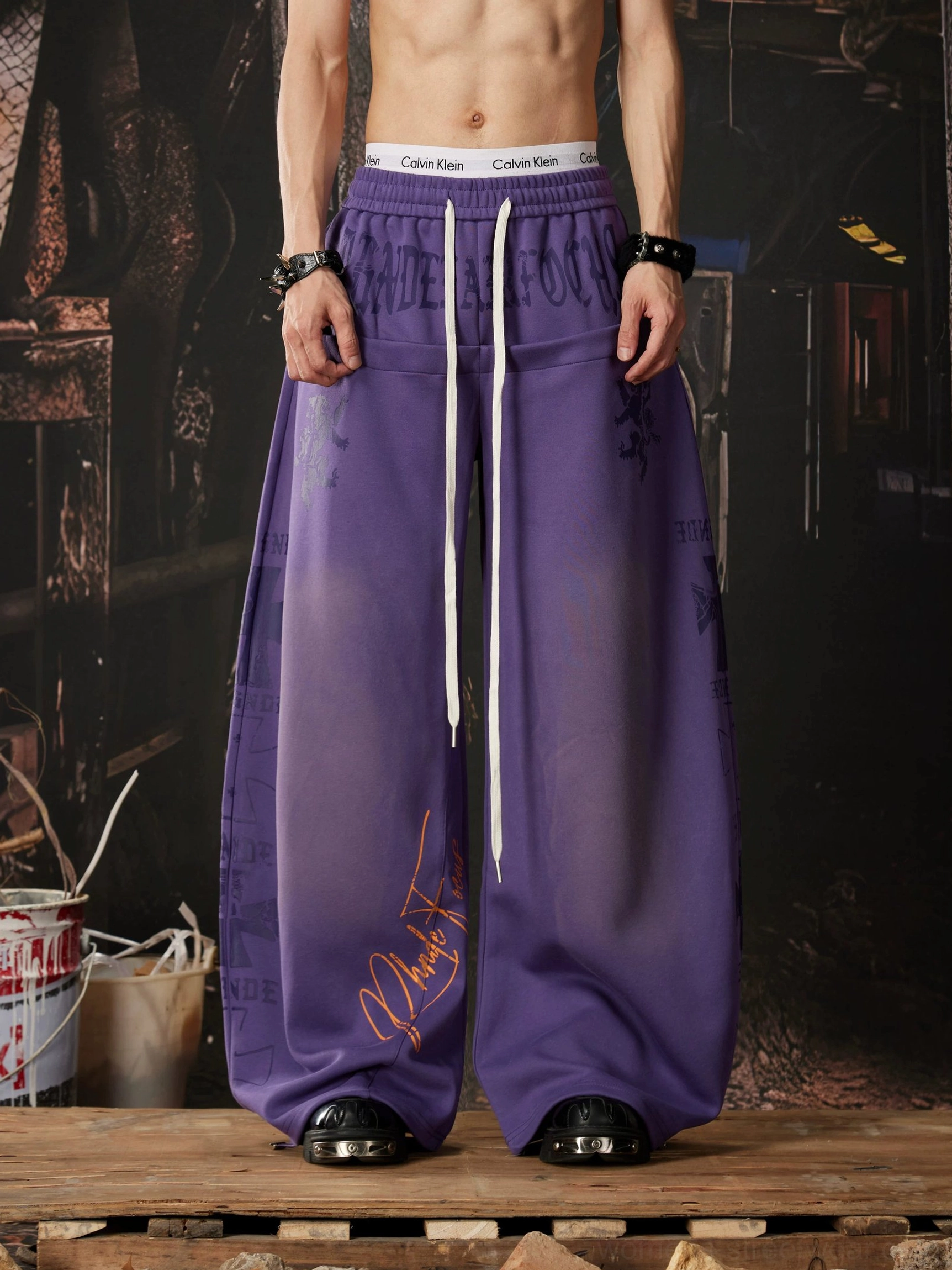 Gradient purple Y2K wide leg streetwear sweatpants with elastic drawstring waist, handwritten graffiti graphics, and ultra-baggy stacked silhouette