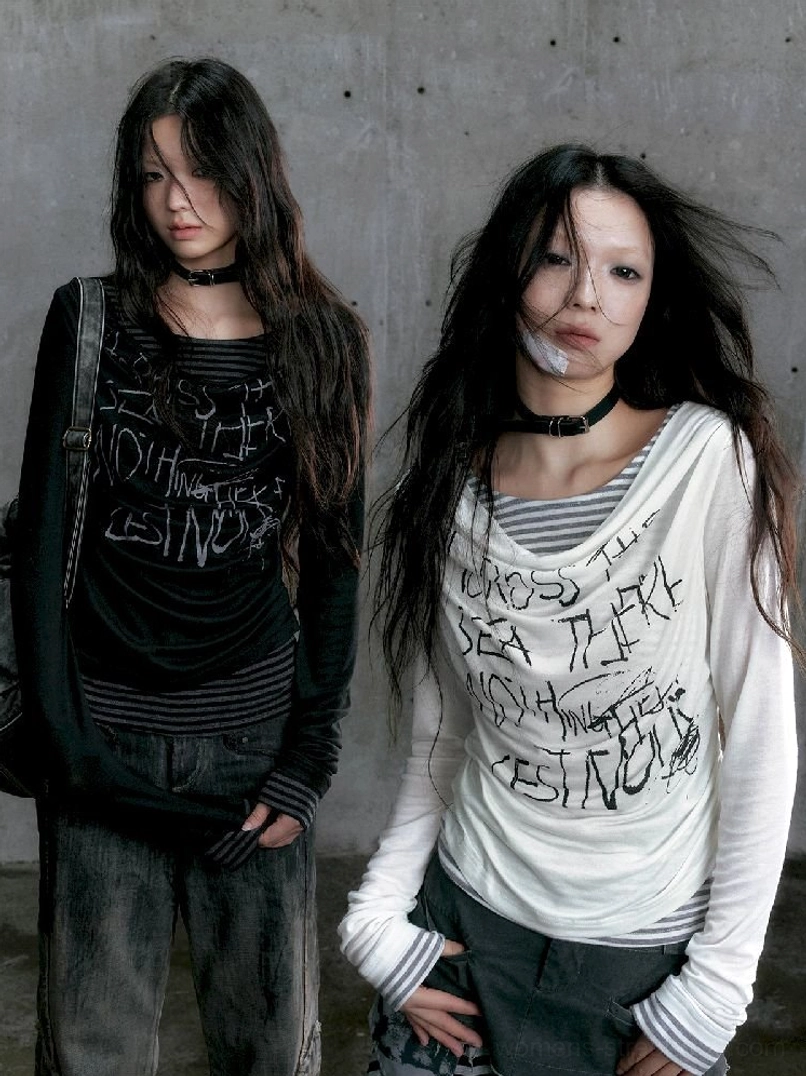 Black and white graffiti layered long sleeve tops styled together in an industrial concrete studio