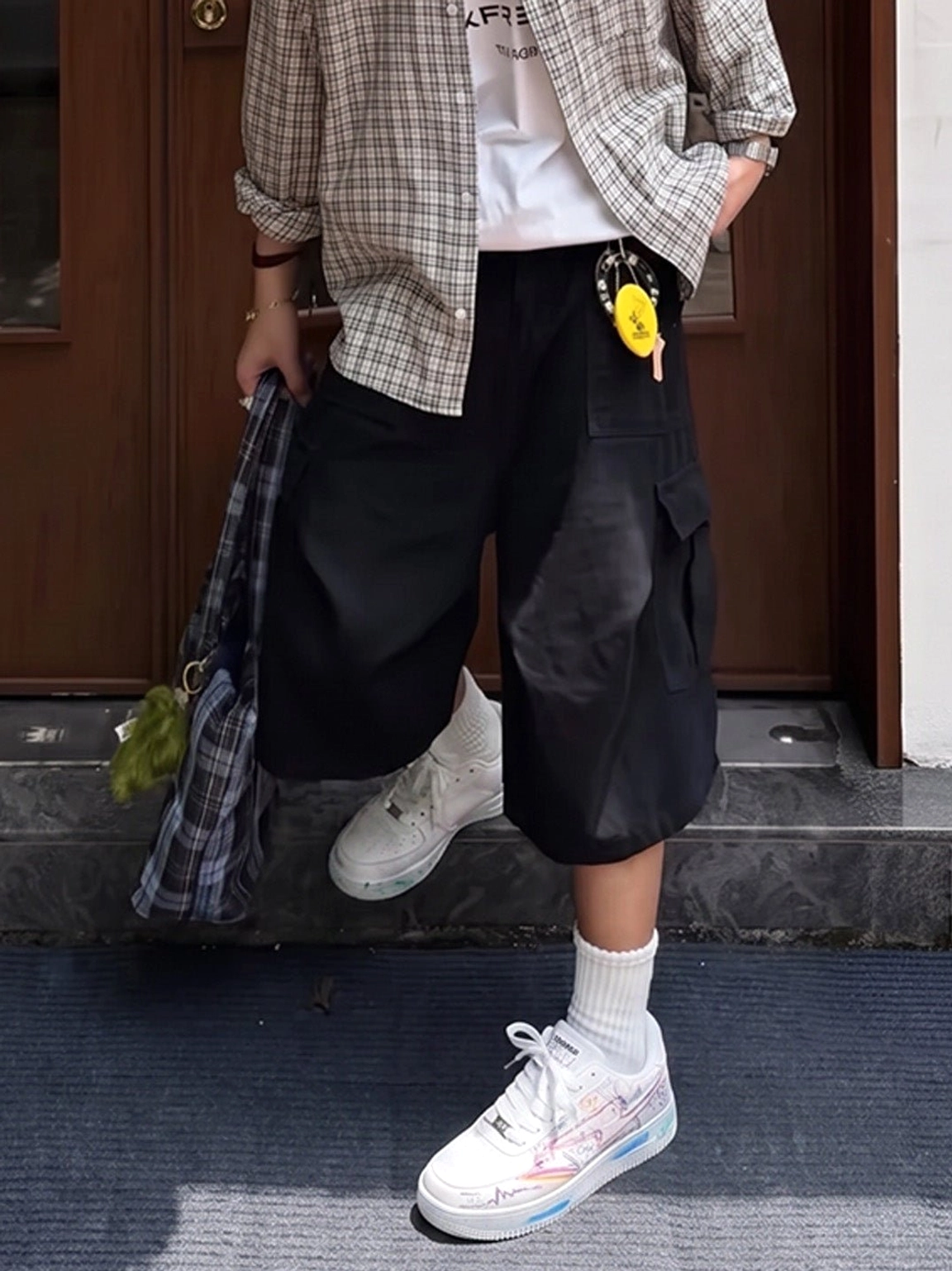 Colorful graffiti low-top court sneakers worn with white socks and black cargo shorts in an urban streetwear outfit