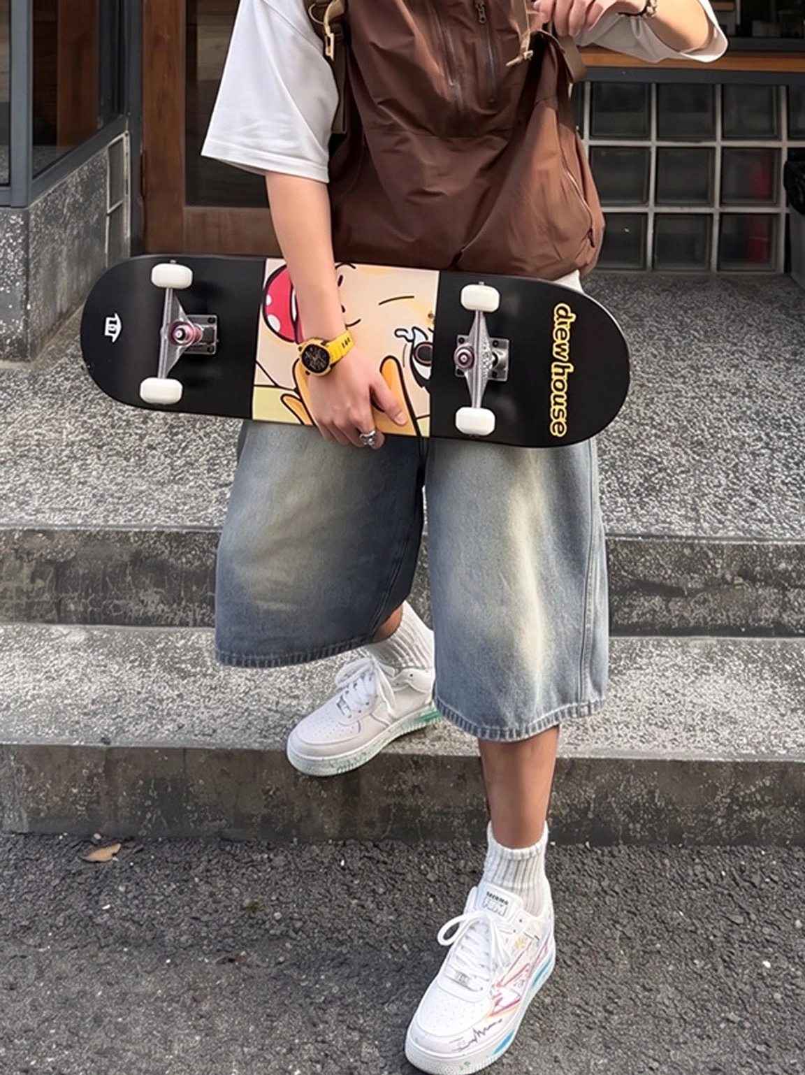 Graffiti lightning low-top court sneakers styled with white crew socks and denim shorts on outdoor stone stairs with skateboard