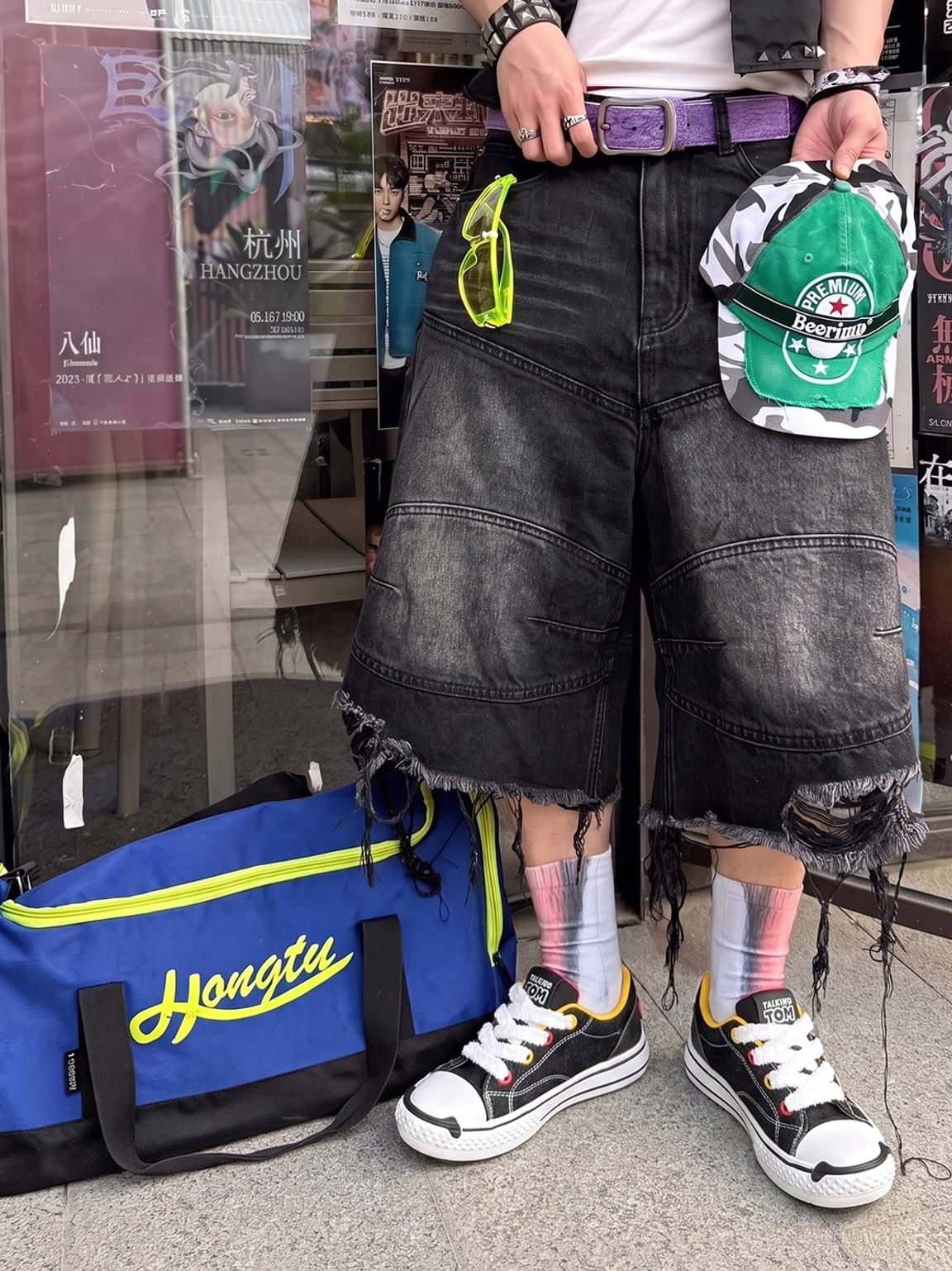 Graphic chunky streetwear sneakers styled with ripped denim shorts and colorful socks in an outdoor urban shop setting
