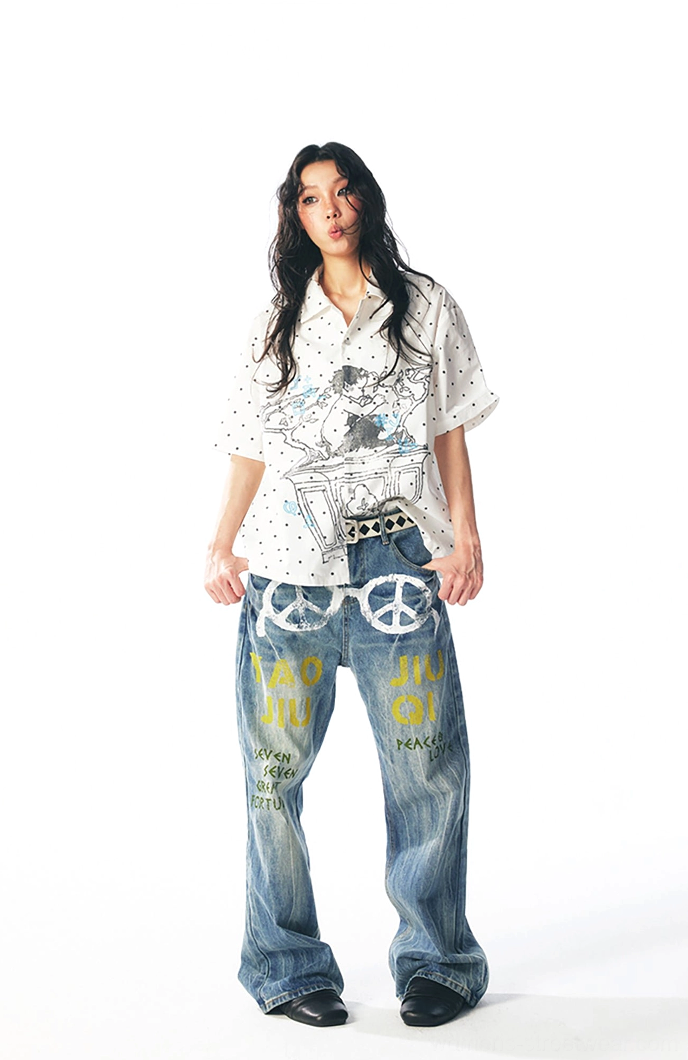 Full body view of a playful white graphic polka dot shirt paired with blue washed printed denim jeans