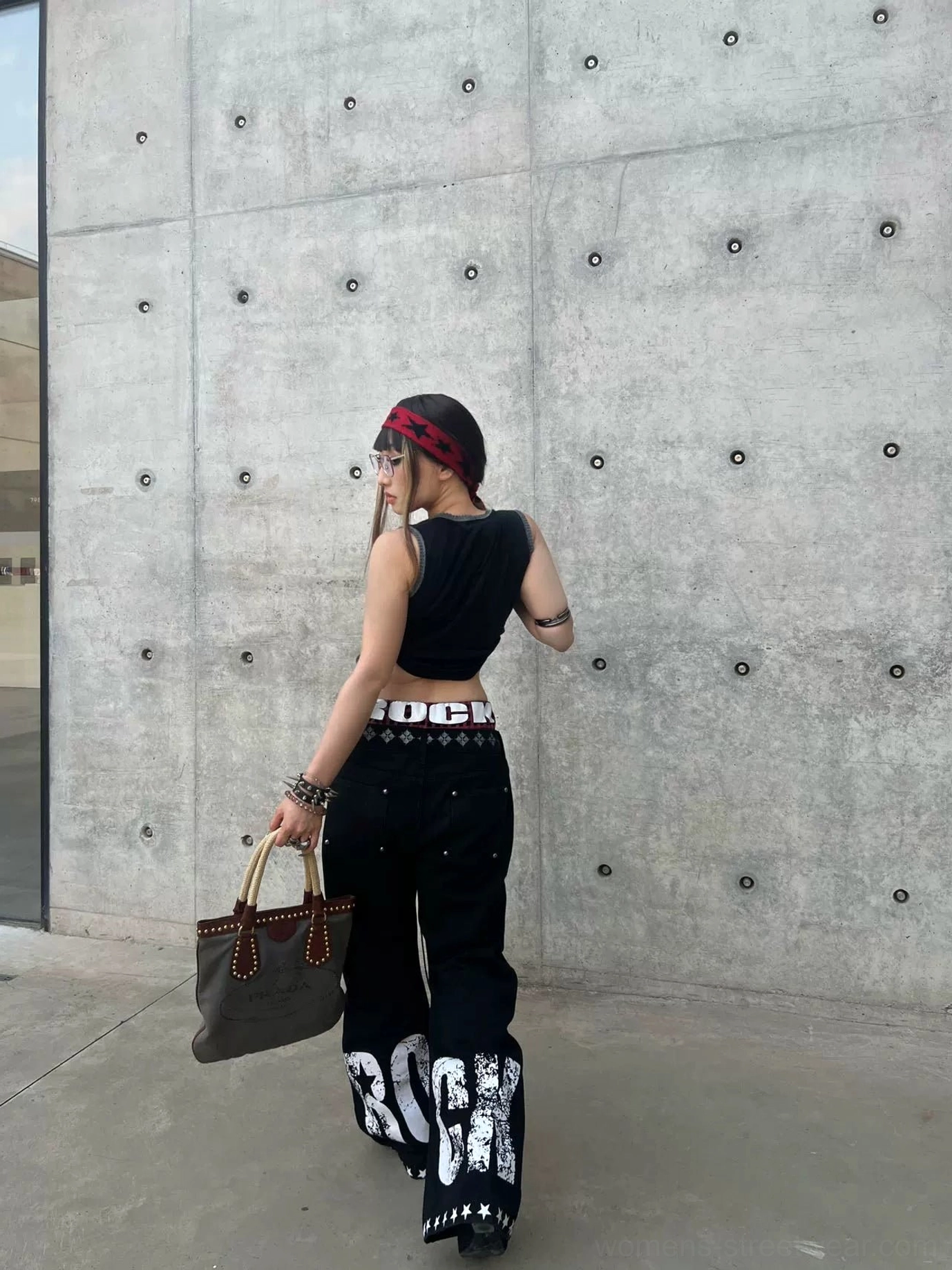 Back view of graphic print black flared jeans featuring distressed ROCK lettering, star stitch hem trim, and alternative streetwear styling