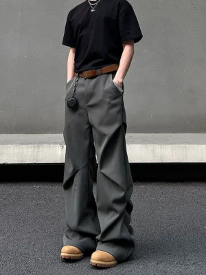 Graphite gray oversized wide-leg drape trousers styled with a black T-shirt brown leather belt and tan work boots in an industrial streetwear setting
