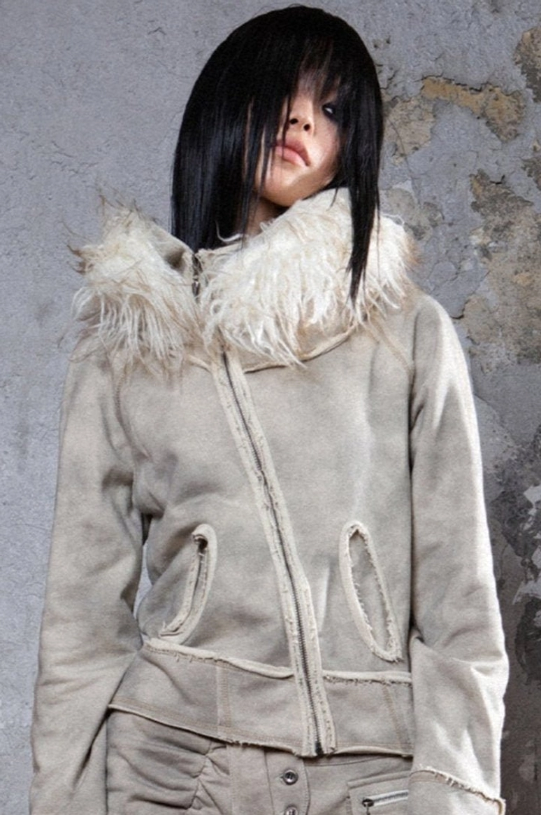 Gray asymmetrical zip jacket with wide fluffy faux fur hood trim, exposed raw seams, and front patch pockets