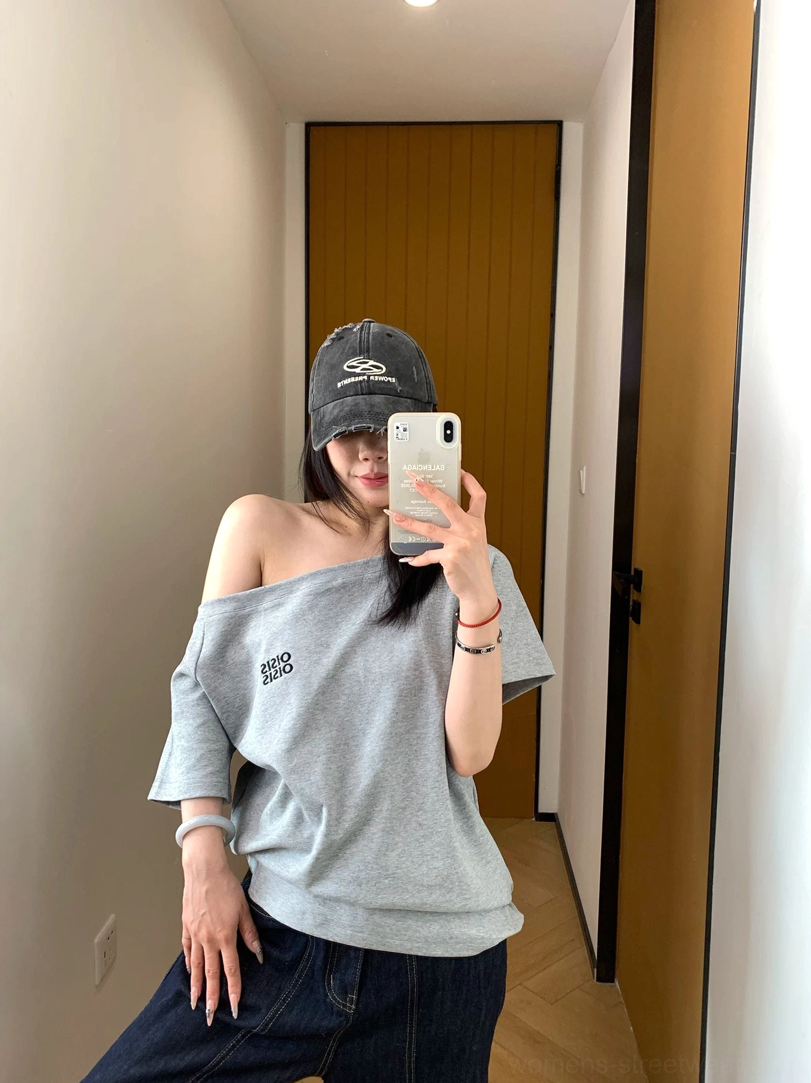 Side mirror view showing the loose fit and one-shoulder neckline of a gray Korean streetwear logo T-shirt with dark denim