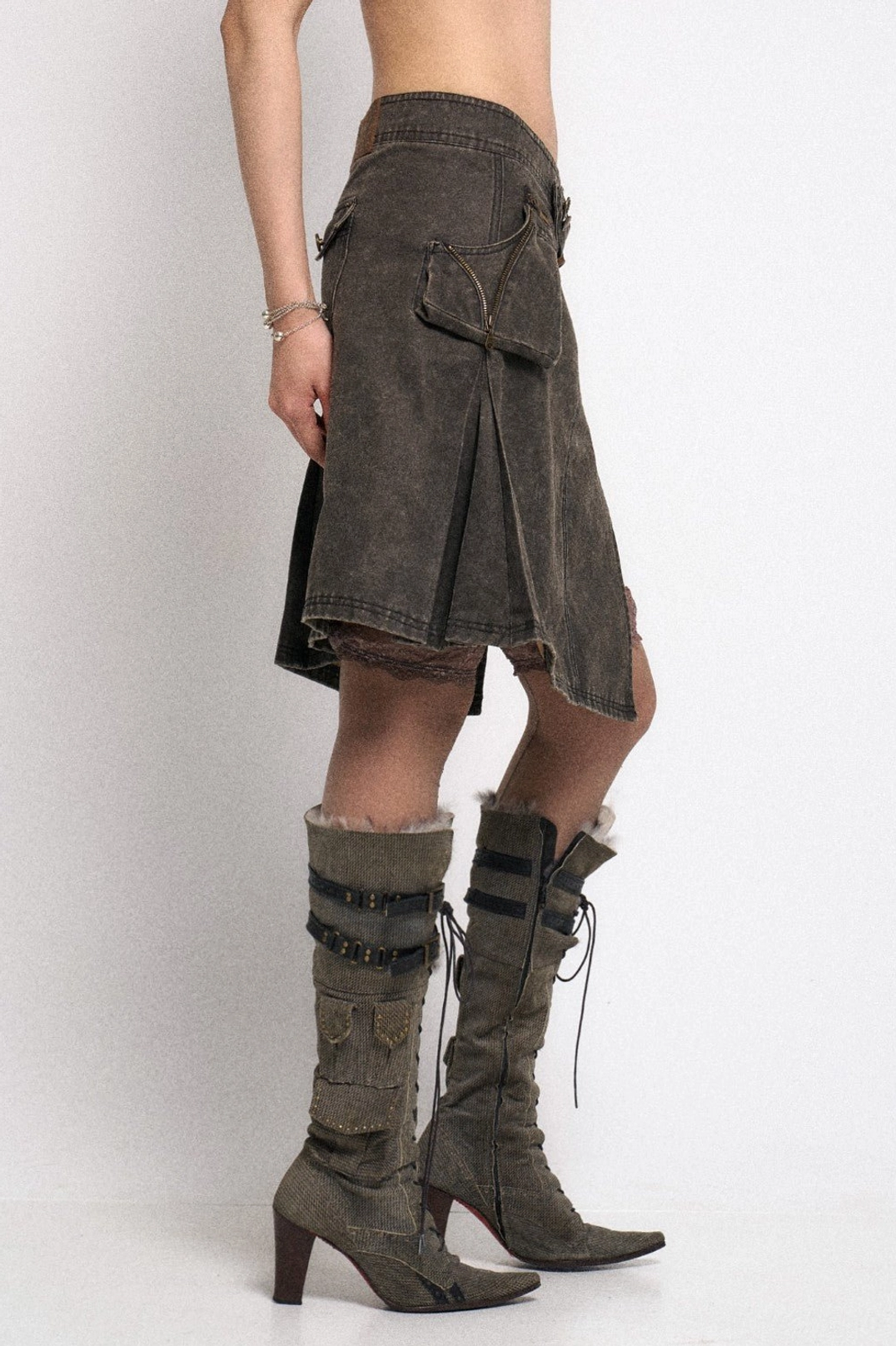 Close side view of gray asymmetrical utility cargo mini skirt with flap pocket waist strap and uneven hem
