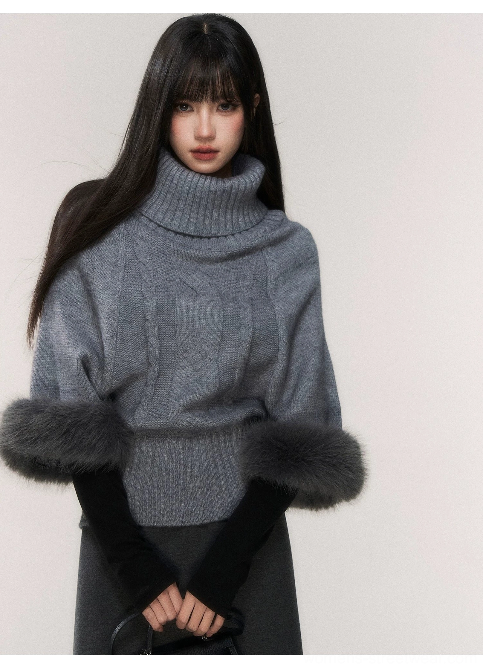 Close-up front view of gray cable knit turtleneck sweater showing thick rolled collar and fluffy faux fur sleeve cuffs
