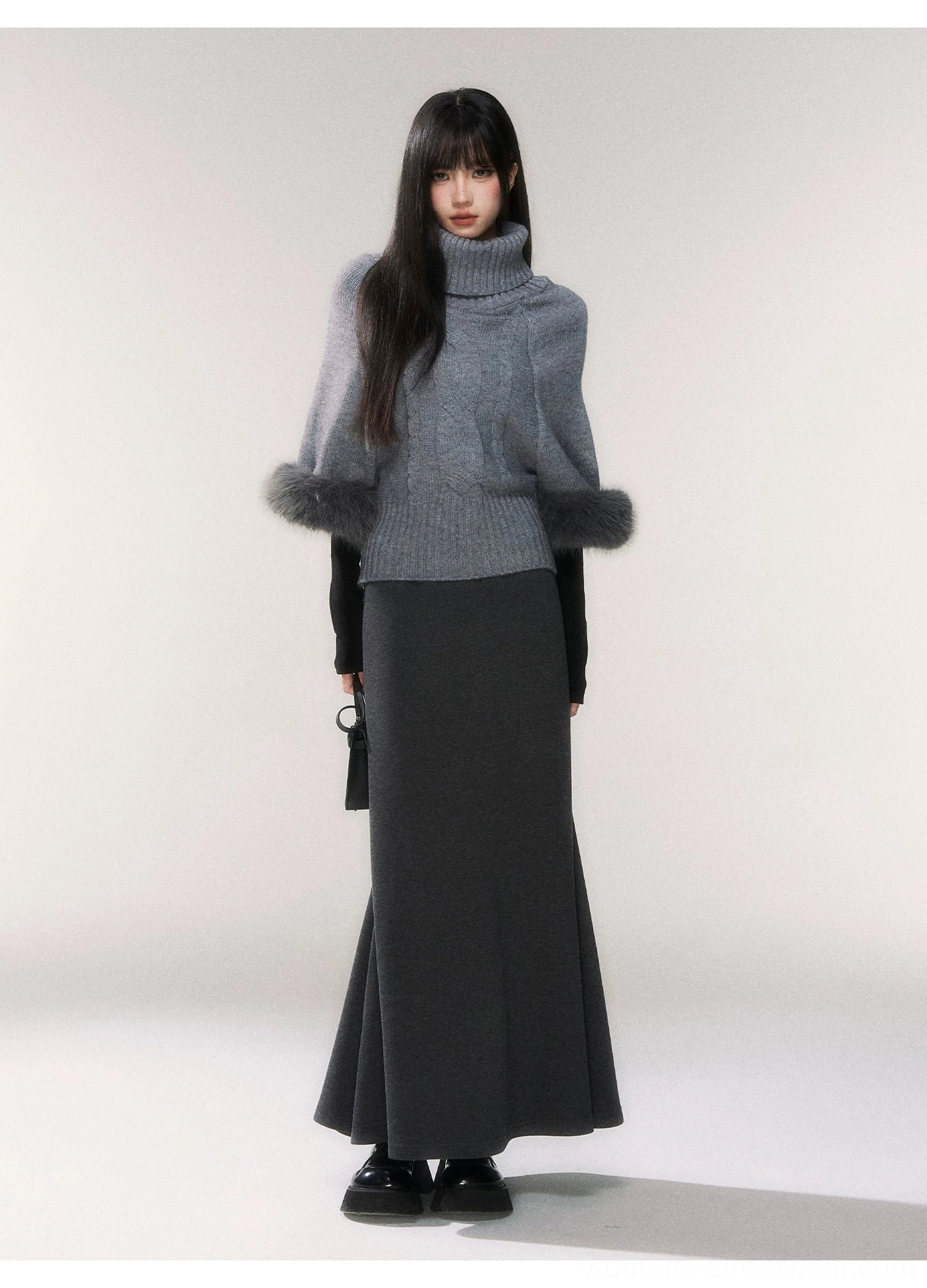 Gray faux fur cuff turtleneck cable knit sweater styled with a dark gray maxi skirt in a full body front studio look