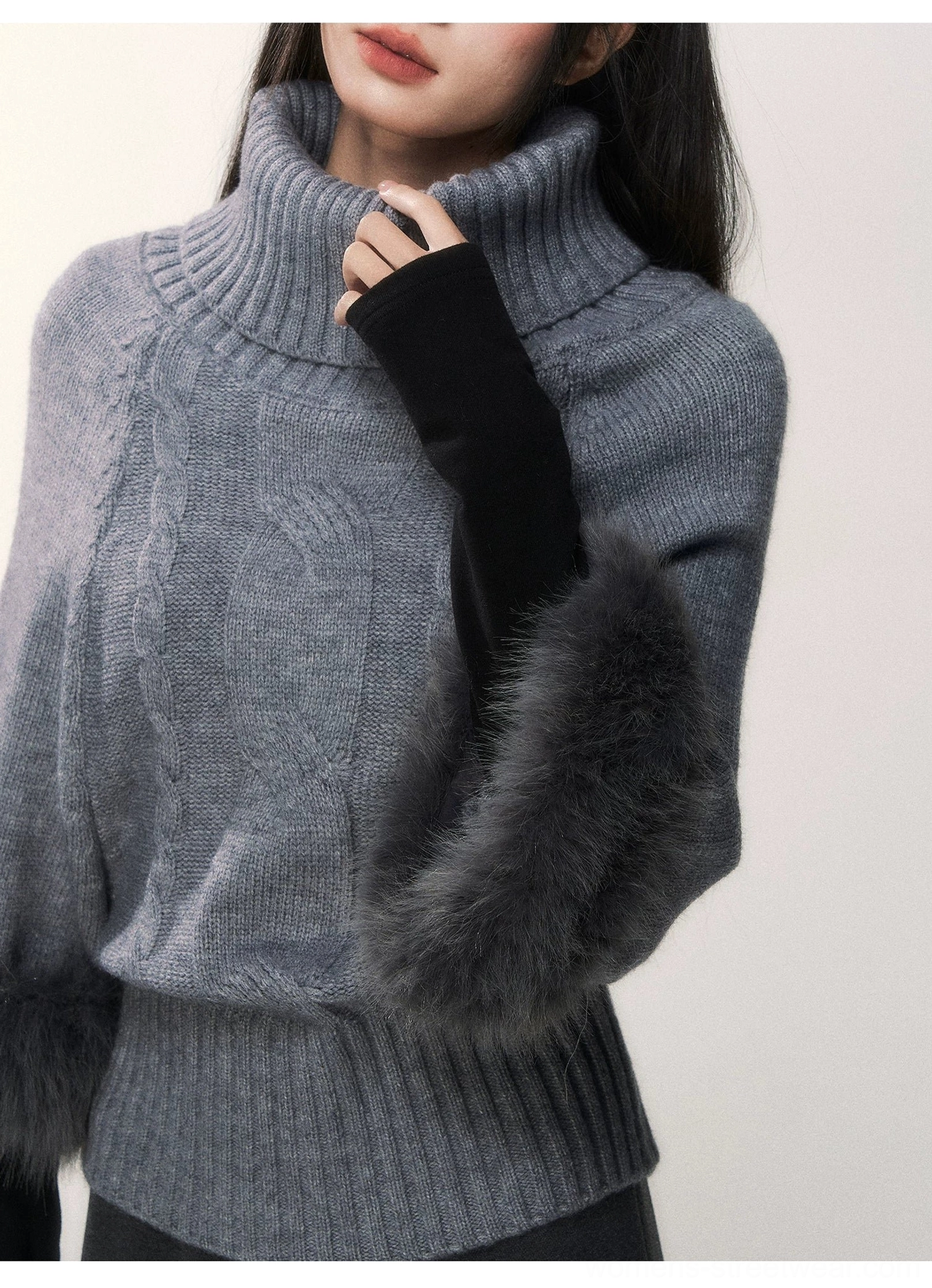 Detailed close-up of ribbed turtleneck collar cable knit texture black sleeve finish and fluffy gray faux fur cuff